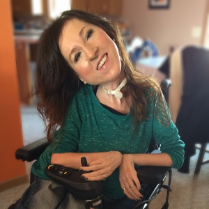 Tashauna Swanson, smiling, sitting in a power wheelchair.