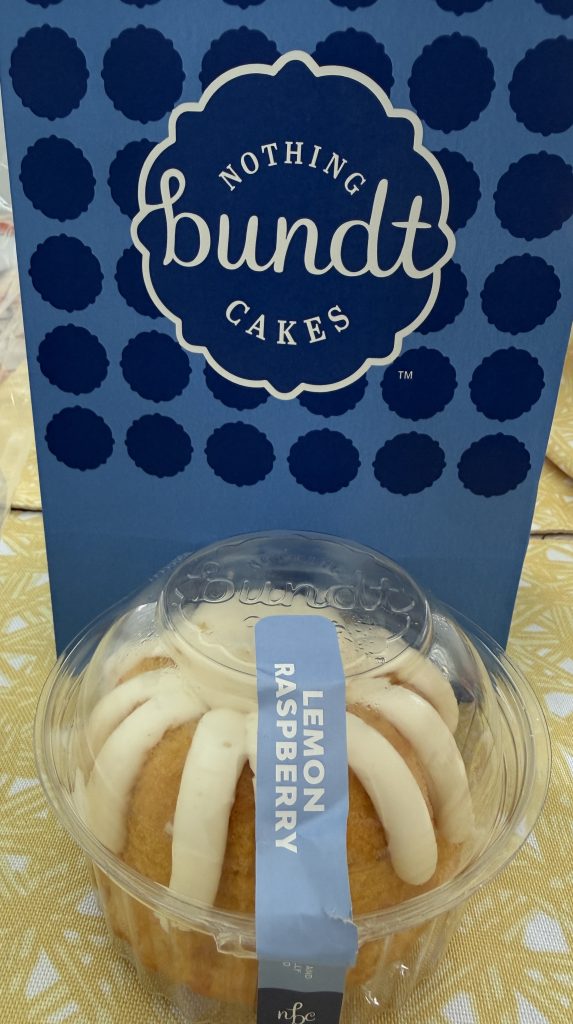 Nothing bundt cake with the company's blue and white branding bag behind the lemon raspberry cake.