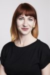 White female with red hair and a black blouse smiling at the camera. Chaya writes about this year's presidential candidates
