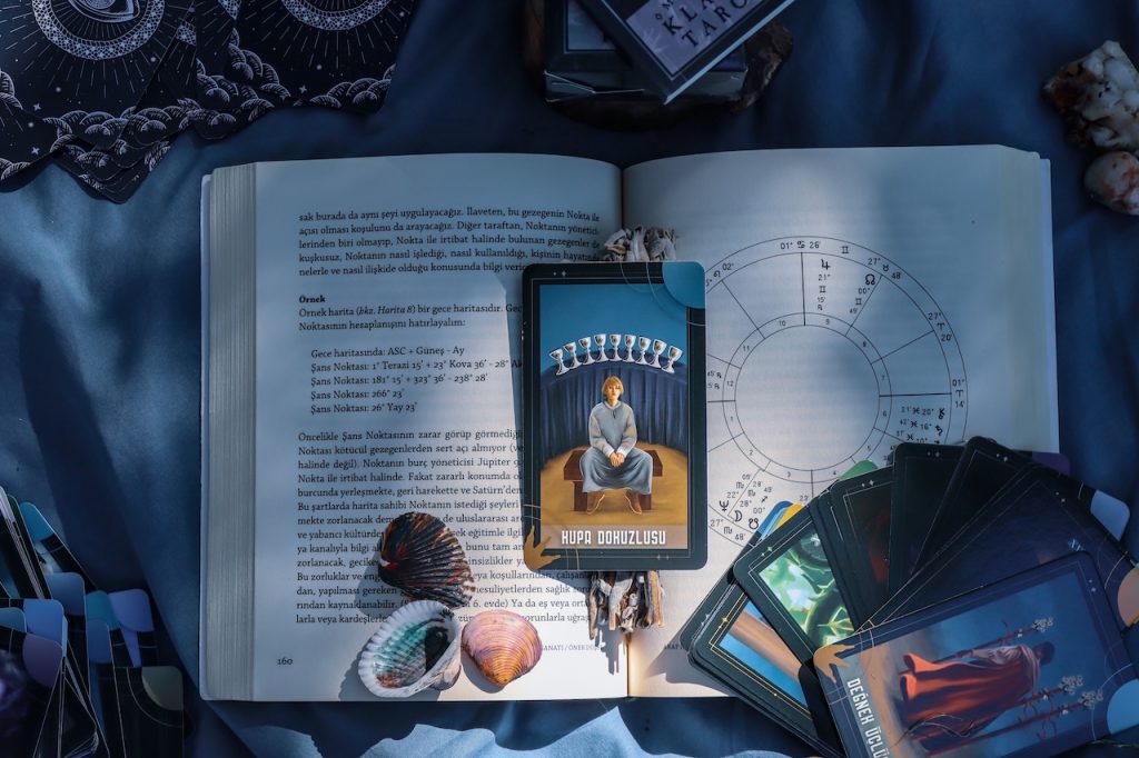 September 2026 horoscope shows an open book with a tarot card on the top.