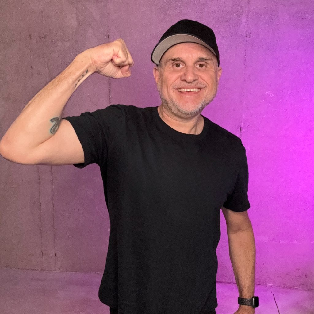 Tony Jacobsen smiles at the camera with his right arm flexing
