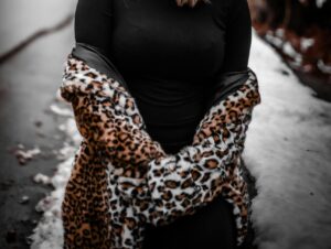 Upclose without showing the face of someone wearing a black long turtle neck sweater and an animal print jacket