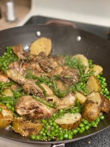 peas, carrots, sliced potatoes and chicken cooking in a wok