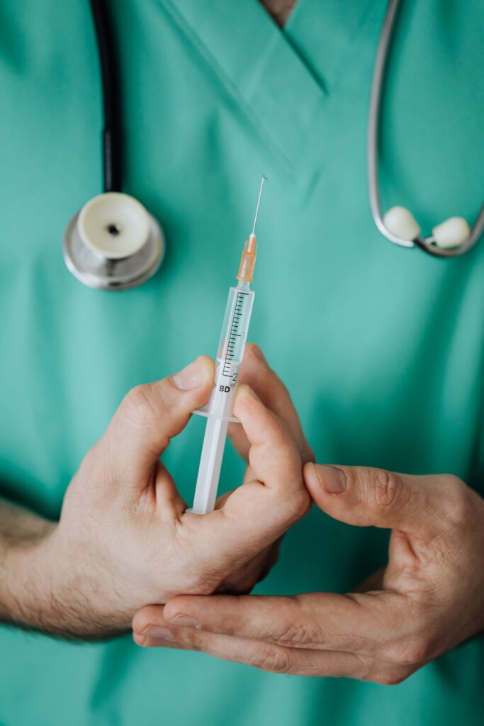 up close image of a man holding a syringe upward.