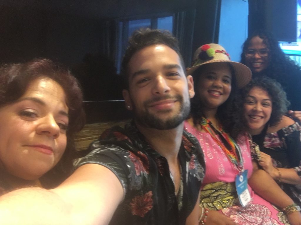 group selfie. Five Latinos. Nathasha is on one side, Billy, a male with a well trimmed beard, his arm is extended. It appears he's the one holding the camera phone. Next to him farther back is a darker Latina with a sun hat on. Behind her, a Latina with curly hair. Behind her, is another darker complexion latina. All are smiling.
