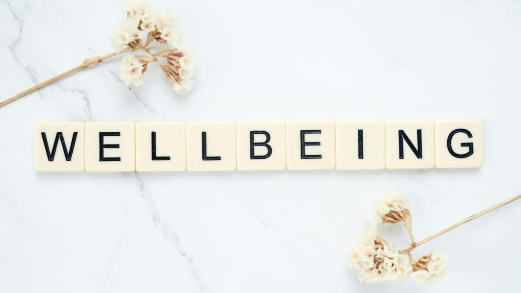 mind body connection scrabble tiles spelling WELLBEING
