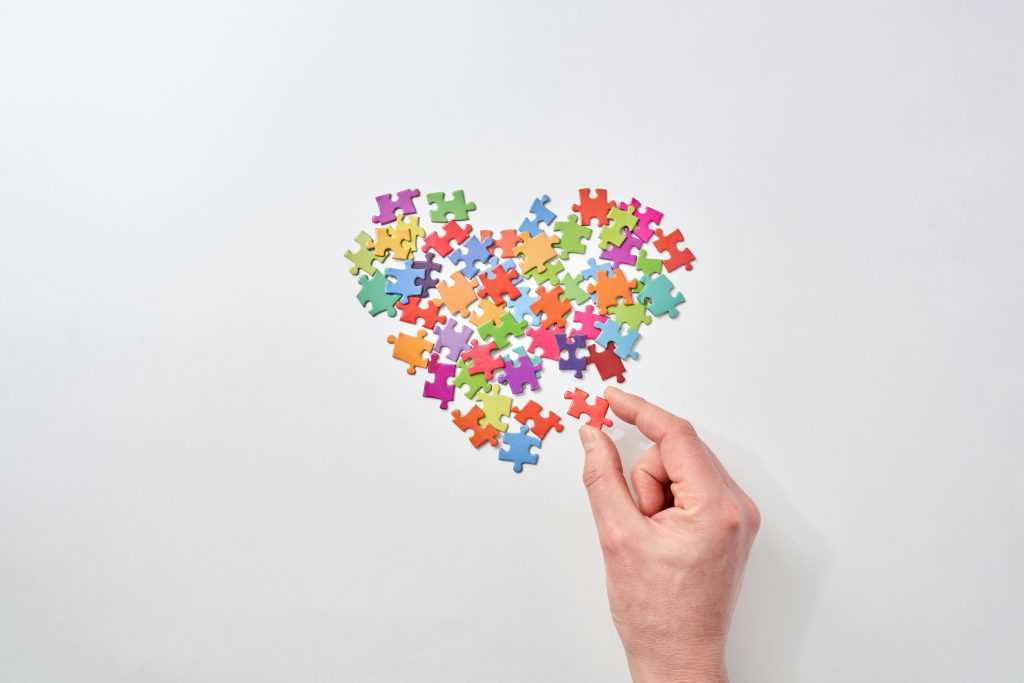 puzzles pieces forming a heart shape with a white hand hold the last piece